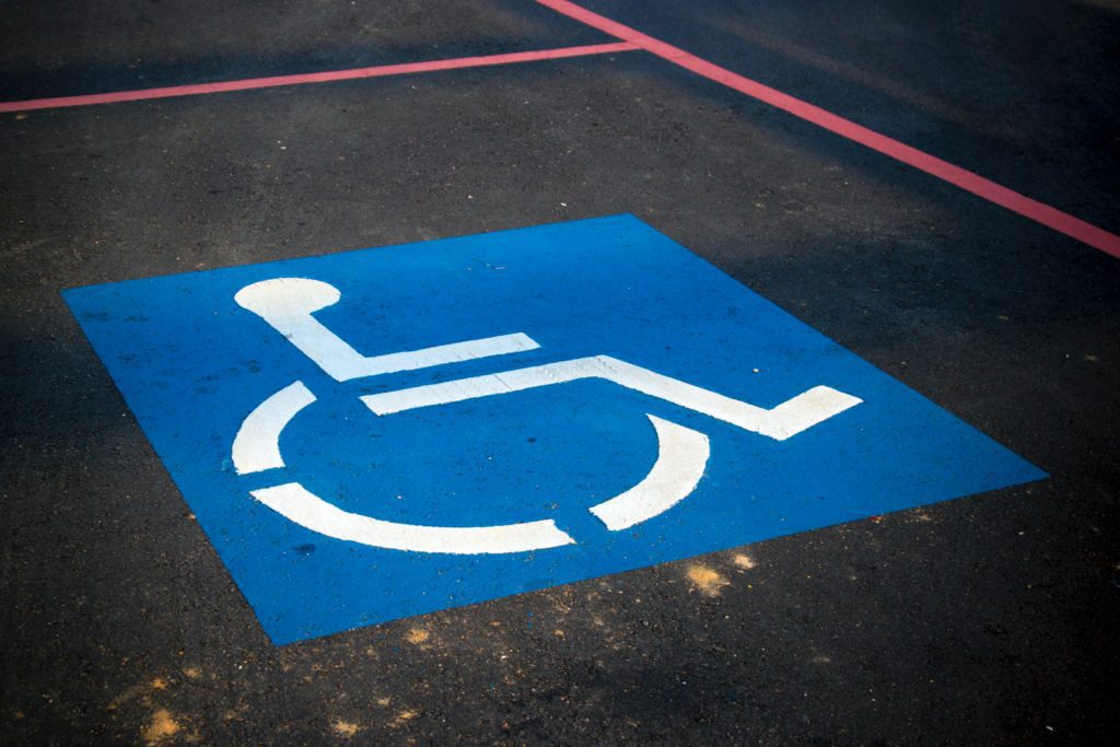 A imagem mostra o símbolo de cadeirante em uma vaga de estacionamento.